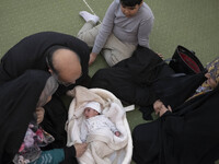 An Iranian family is sitting around a newborn baby in the Imam Khomeini Grand Mosque, attending the 31st edition of the International Holy Q...