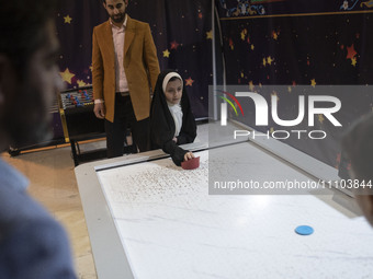 A young veiled Iranian girl is playing air hockey in the Imam Khomeini Grand Mosque at the 31st edition of the International Holy Quran Exhi...