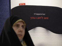 A veiled Iranian woman is standing in front of an anti-Western media poster at the Imam Khomeini Grand Mosque during the 31st edition of the...