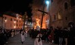 People wearing white hooded costumes and bringing Jesus Christ cross are seen next to a gi...