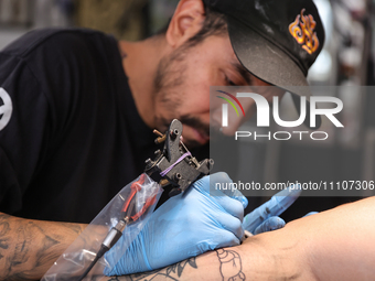 Israel Ortega, also known as Mr. Kaliman, is tattooing a person's leg at a tattoo salon in the Iztapalapa neighborhood of Mexico City, Mexic...