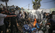 Palestinians are checking the damage at a makeshift camp for displaced people in front of...