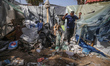 Palestinians are checking the damage at a makeshift camp for displaced people in front of...