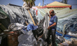 Palestinians are checking the damage at a makeshift camp for displaced people in front of...