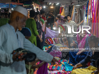 Customers are gathering at a market to purchase dresses from a weekly market in a low-income area ahead of Eid ul Fitr in Dhaka, Bangladesh,...