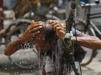 A rickshaw puller is wetting his head at a roadside tap to find relief from a heatwave in Dhaka, Bangladesh, on April 6, 2024. According to...