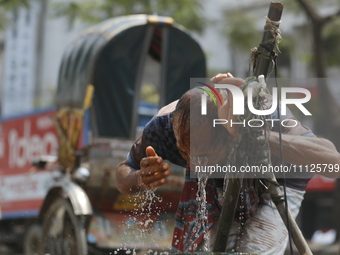 A rickshaw puller is wetting his head at a roadside tap to find relief from a heatwave in Dhaka, Bangladesh, on April 6, 2024. According to...
