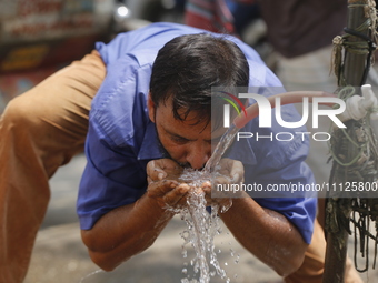 An auto-rickshaw driver is drinking water from a roadside tap to find relief from a heatwave in Dhaka, Bangladesh, on April 6, 2024. The Met...