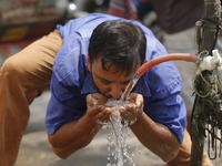 An auto-rickshaw driver is drinking water from a roadside tap to find relief from a heatwave in Dhaka, Bangladesh, on April 6, 2024. The Met...
