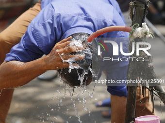 An auto-rickshaw driver is wetting his head at a roadside tap to get relief from a heatwave in Dhaka, Bangladesh, on April 6, 2024. Accordin...