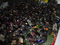 Motorbikes belonging to passengers are being parked on the ship that is set to take them to their hometowns ahead of Eid al-Fitr, known as '...