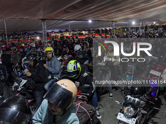 Motorbike riders are waiting in line to board a ship that will take them to their hometown ahead of Eid al-Fitr, known as 'Mudik', at Ciwand...