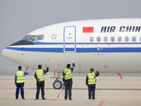 Ground crew members are waving to a passenger plane as it is being released at Yantai Penglai International Airport in Yantai, China, on Apr...