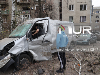 Two men are examining a damaged van after a Russian precision-guided munition hit civil infrastructure in Kharkiv, northeastern Ukraine, on...