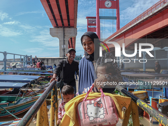 People are waiting for the ship to depart at Pier 16 Ilir in Palembang, Indonesia, on April 8, 2024. Millions of people are traveling back f...