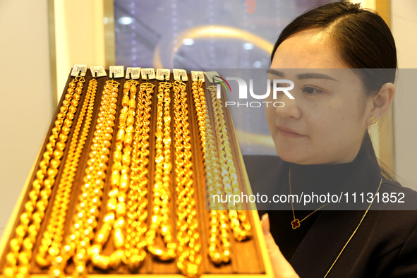 A staff member is arranging gold ornaments for sale at a gold shop in the Lianyun district, Lianyungang City, China, on April 9, 2024. 