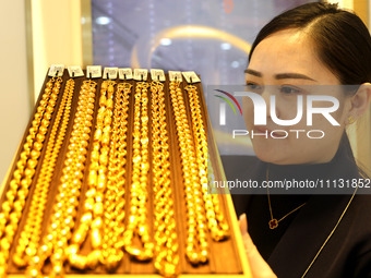 A staff member is arranging gold ornaments for sale at a gold shop in the Lianyun district, Lianyungang City, China, on April 9, 2024. (