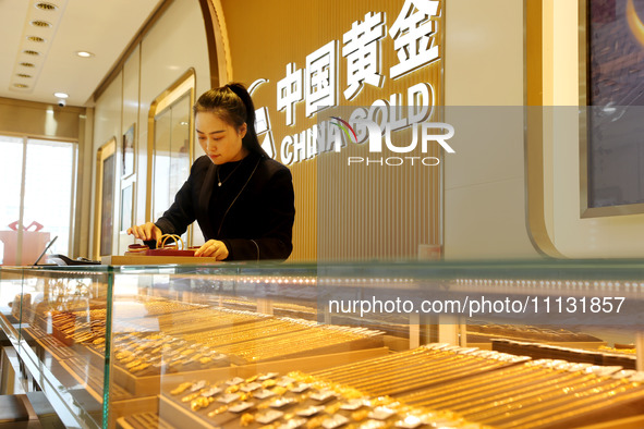 A staff member is arranging gold ornaments for sale at a gold shop in the Lianyun district, in Lianyungang, China, on April 9, 2024. 