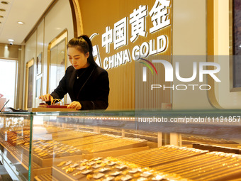 A staff member is arranging gold ornaments for sale at a gold shop in the Lianyun district, in Lianyungang, China, on April 9, 2024. (