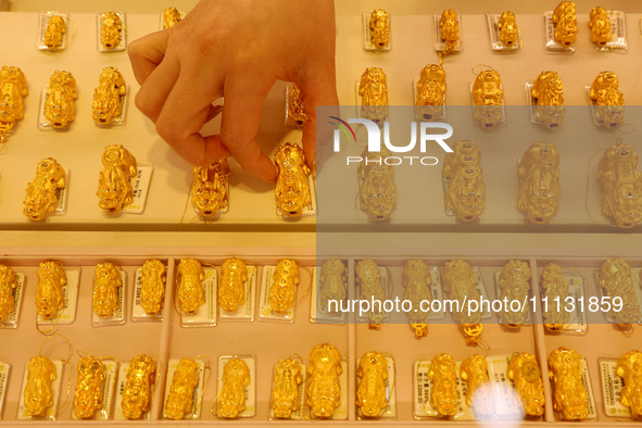 A staff member is arranging gold ornaments for sale at a gold shop in the Lianyun district, Lianyungang City, Jiangsu Province, East China,...