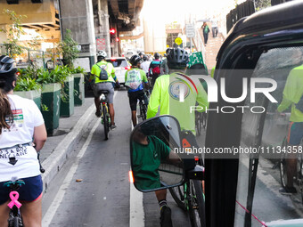 Cyclists are accompanying a man who is driving an electric tricycle during a ride-out protest to the headquarters of the Metro Manila Develo...
