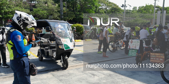 An enforcer from the Metro Manila Development Agency (MMDA) is looking on as cyclists and light electric vehicle users are standing outside...