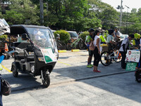 An enforcer from the Metro Manila Development Agency (MMDA) is looking on as cyclists and light electric vehicle users are standing outside...