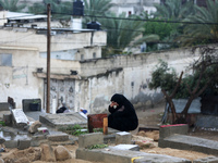A Palestinian woman is praying at a cemetery on the grave of a relative during the first day of Eid al-Fitr, the Muslim holiday that begins...