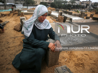 A Palestinian woman is praying at a cemetery on the grave of a relative during the first day of Eid al-Fitr, the Muslim holiday that begins...