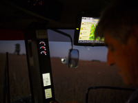 Walter is driving the combine at dusk, harvesting a soybean field. (