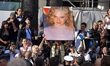 Fans sit outside the premiere of Grace of Monaco, with an oversized Nicole Kidman poster a...
