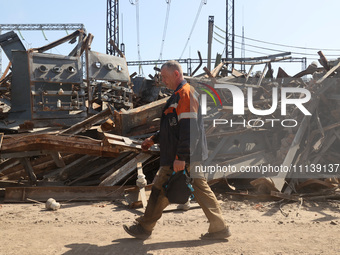 A utility worker is walking past a pile of debris at an energy facility that is being repaired after being damaged by Russian shelling in Kh...