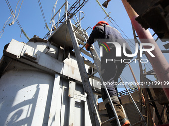 A utility worker is climbing a ladder at an energy facility that is being repaired after being damaged by Russian shelling in Kharkiv, north...