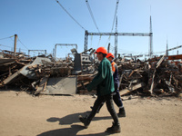 Utility workers are walking past a pile of debris at an energy facility that is being repaired after damage from Russian shelling in Kharkiv...