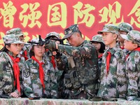 An instructor at a military experience camp is explaining the use of weapons to primary school students in Lianyungang, China, on April 13,...