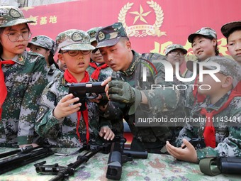 An instructor at a military experience camp is explaining the use of weapons to primary school students in Lianyungang, China, on April 13,...