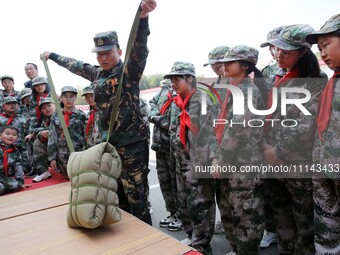 A military experience camp instructor is teaching primary school students how to carry a backpack in Lianyungang, China, on April 13, 2024....