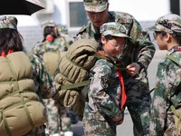A military experience camp instructor is teaching primary school students how to carry a backpack in Lianyungang, China, on April 13, 2024....