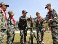 An instructor at a military experience camp is teaching elementary school students how to simulate the firing of a ''mortar'' in Lianyungang...