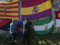 Two volunteers are hanging flags, including the Republican one and that of the anarchists of the CNT, on one of the walls of the Valdenoceda...