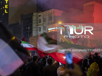 Iranians are waving Iranian flags as they celebrate Iran's IRGC UAV and missile attack against Israel in downtown Tehran, Iran, on April 14,...