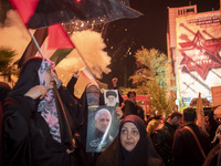 An elderly Iranian woman is holding portraits of Iran's Supreme Leader, Ayatollah Ali Khamenei (top), and the former commander of the Islami...