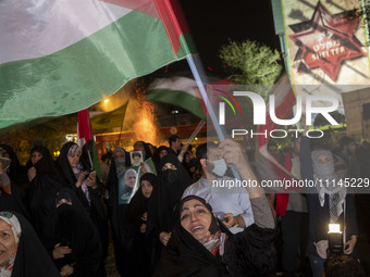A veiled Iranian woman is waving a Palestinian flag while participating in a celebration of Iran's IRGC UAV and missile attack against Israe...