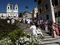 Tourists are taking photos near azalea plants on the Trinita dei Monti steps in Rome, Italy, on April 14, 2024. (
