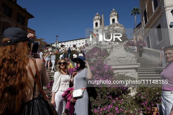 Tourists are taking photos near azalea plants on the Trinita dei Monti steps in Rome, Italy, on April 14, 2024. 