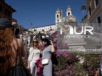 Tourists are taking photos near azalea plants on the Trinita dei Monti steps in Rome, Italy, on April 14, 2024. (