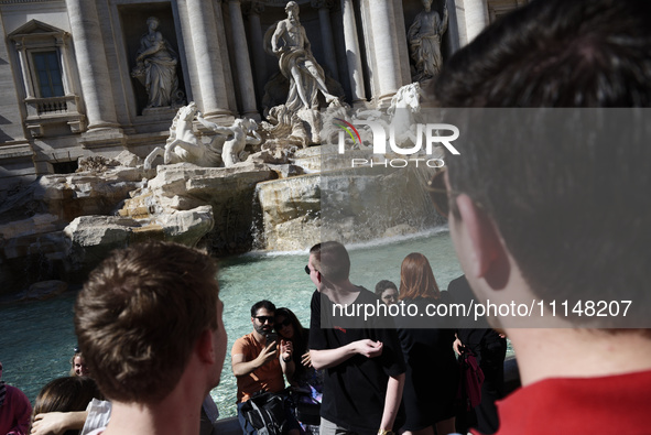 Tourists are shooting photos and throwing coins into the Trevi Fountain to ensure their return in Rome, Italy, on April 14, 2024. 