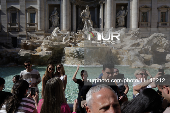 Tourists are shooting photos and throwing coins into the Trevi Fountain to ensure their return in Rome, Italy, on April 14, 2024. 
