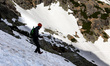 A tourist walks on a mountain slope on snow amid picturesque views on a mountain range in...