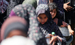 Displaced Palestinians are gathering to receive food at a donation point in Deir al-Balah,...